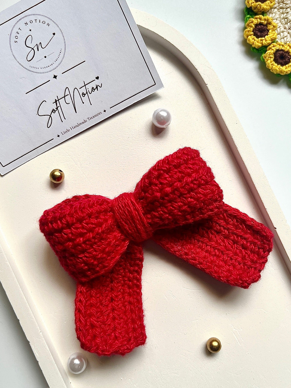 Two red crochet bows side by side on white tray