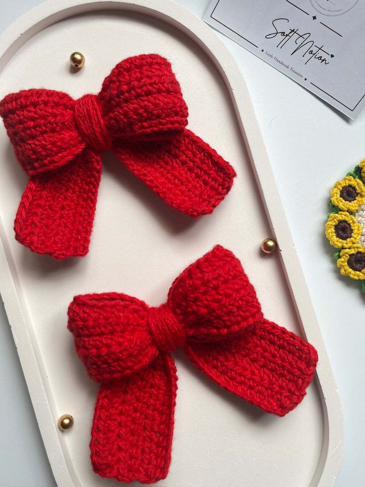Close-up of red crochet bow with pearl and gold bead details