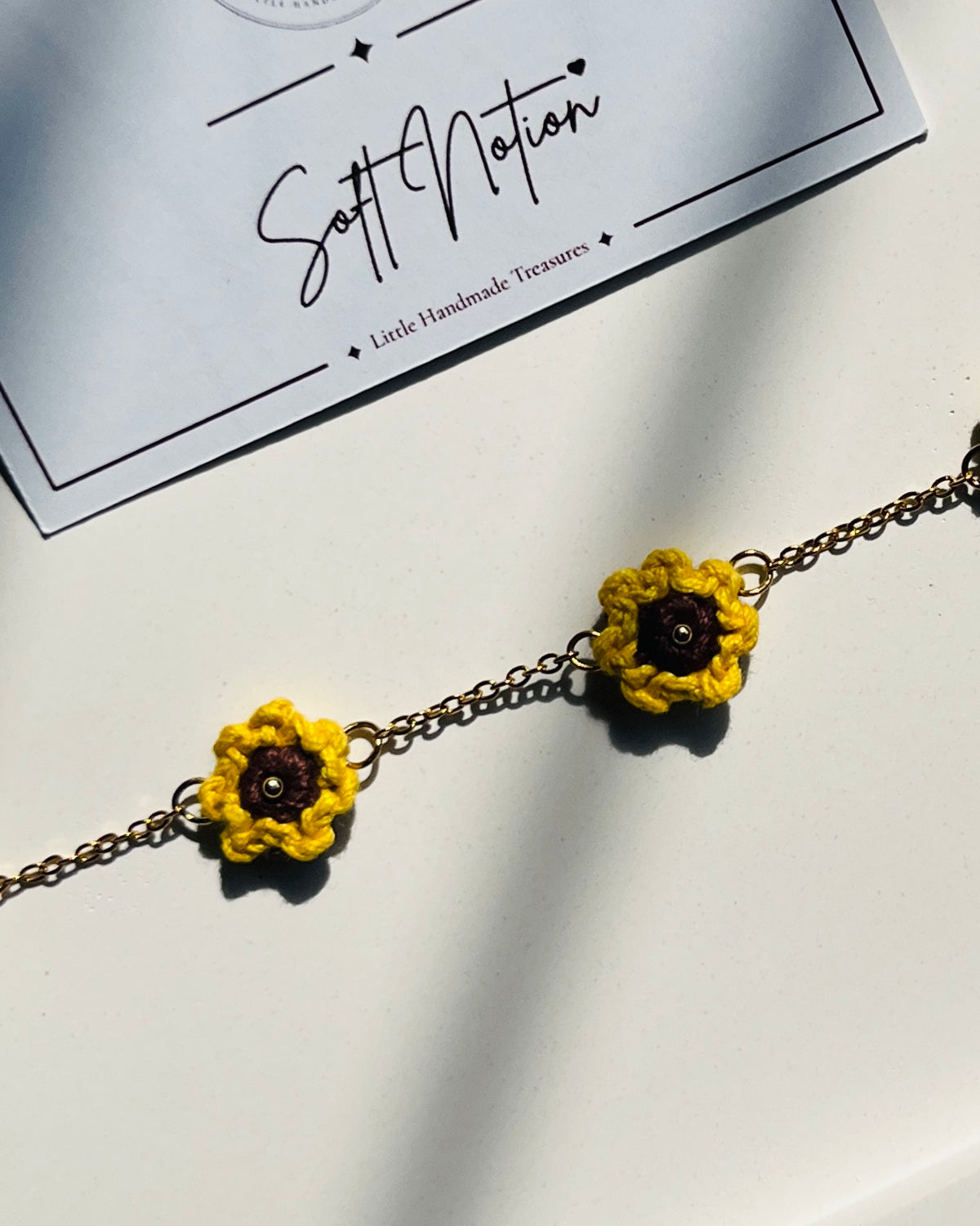 Close-up of Sunshine Anklet with miniature hand-crocheted sunflower charms on a gold-toned chain