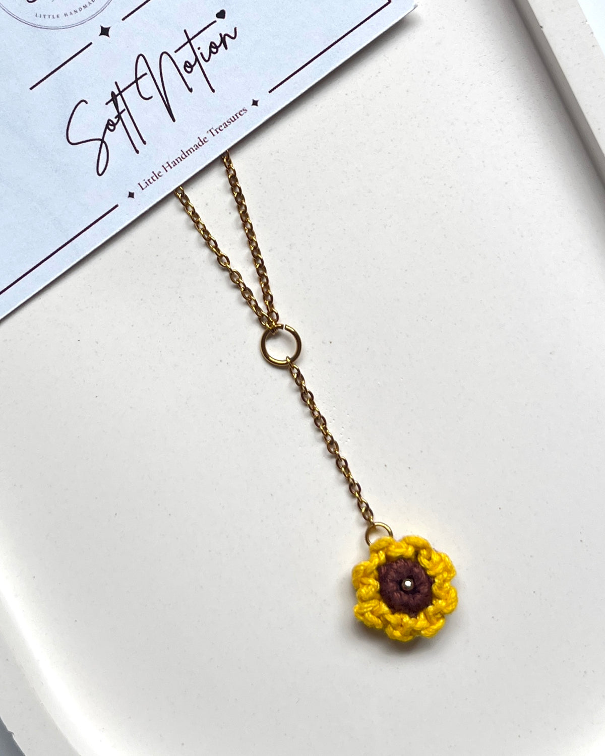 Close-up of Sunshine Necklace with hand-crocheted sunflower charm and gold-toned drop chain